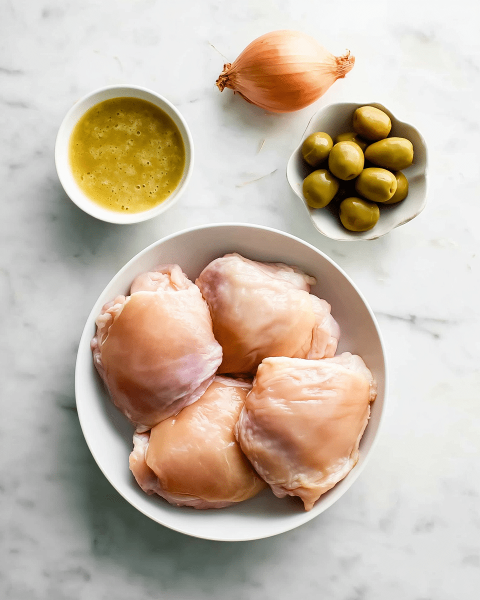 Four pieces of raw chicken thighs with smooth, light pink skin rest closely together in a white bowl. Above the bowl, slightly to the right, sits a small white bowl containing green olives that shine with a light gloss. To the upper left of the olives, another small white bowl holds a thick, pale yellow sauce with a slightly uneven texture. To the upper right of this bowl, there is one whole light brown onion with a dry stem end. All items are placed on a white marbled surface. Photo taken with an iphone --ar 4:5 --v 7