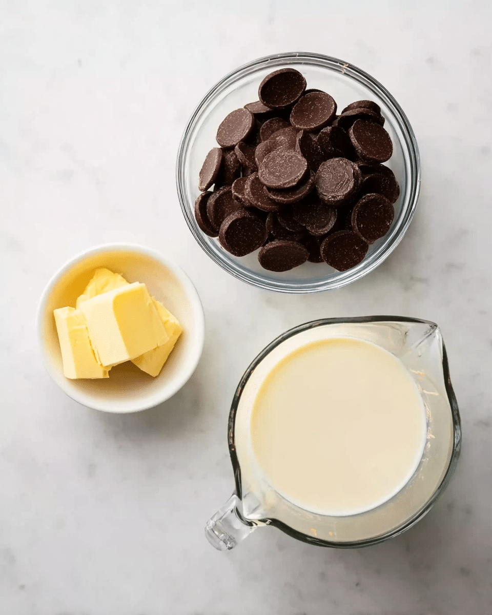 The image shows three containers on a white marbled surface. At the top left, there is a small white bowl with a square piece of yellow butter. To the right, a medium clear glass bowl is filled with round dark brown chocolate discs stacked unevenly. Below these, a clear glass measuring cup holds a creamy white liquid, filling about half of it. The scene is clean and bright with simple kitchen items arranged neatly photo taken with an iphone --ar 4:5 --v 7