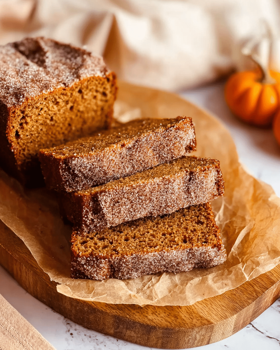 Three slices of brown spiced cake with a sugar and cinnamon topping are stacked slightly overlapped on a piece of brown parchment paper. The parchment sits on a round wooden board placed on a white marbled surface. The texture of the cake looks soft and moist with small air holes visible inside. Parts of the rest of the loaf with the same topping are visible at the edges. A soft white cloth and small pumpkins blur in the background. Photo taken with an iphone --ar 4:5 --v 7