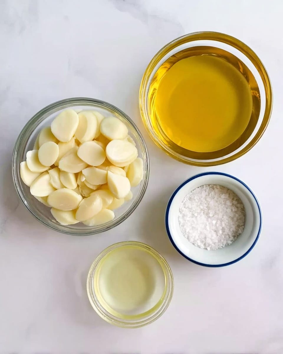The image shows four glass bowls on a white marbled surface. The largest bowl, positioned in the top right, holds a golden yellow liquid with a smooth texture. Below it on the left, a medium sized bowl is filled with peeled garlic cloves, creamy white in color with a slightly shiny surface. Near the bottom center, a smaller glass bowl contains a light yellow translucent liquid. To the right of this, a small white bowl with a blue rim holds coarse white salt, showing a grainy texture. The overall setup looks clean and bright with a simple arrangement. photo taken with an iphone --ar 4:5 --v 7