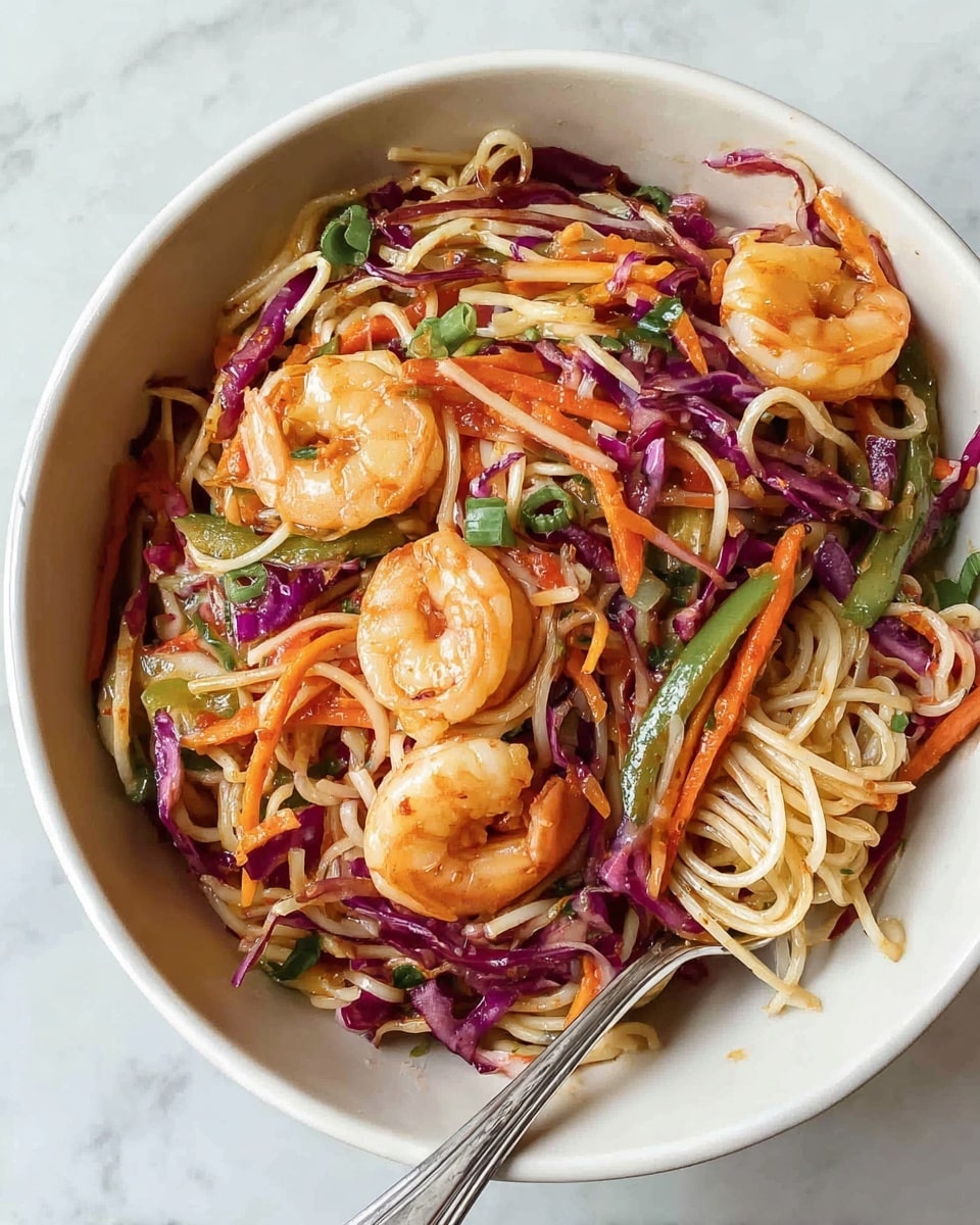 A white bowl filled with a colorful noodle dish featuring thin white noodles intertwined with bright orange carrot strips, deep purple cabbage shreds, and green bell pepper slices, mixed with several pink shrimp scattered on top. The shrimp look tender with a slight sheen, lying across the noodles and veggies, which have a fresh and crunchy texture. A metal fork is partially visible resting inside the bowl on the right side. The bowl sits on a white marbled surface that adds a clean and simple background. photo taken with an iphone --ar 4:5 --v 7