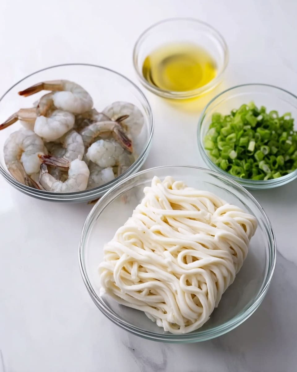 The image shows four clear glass bowls on a white marbled surface, each with different ingredients. The biggest bowl in the front center holds a block of thick, white udon noodles with a soft and slightly curly texture. Behind it on the left is a medium bowl with several raw shrimp that are pale gray with darker tails. To the right of the noodles is a small bowl containing a light yellow liquid. Behind the noodles and shrimp is another small bowl filled with bright green chopped spring onions. The scene is bright and clean with a neat arrangement of the bowls. photo taken with an iphone --ar 4:5 --v 7