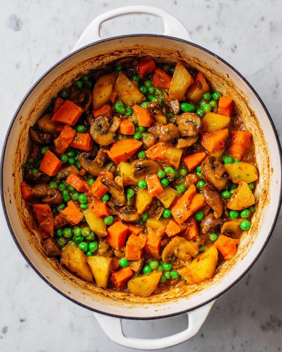 A white pot filled with a cooked vegetable mix sitting on a white marbled surface, showing three main layers: the base layer is light brown sauce coating the inside of the pot, the middle layer consists of bright orange carrot chunks and golden-yellow potato pieces, and the top layer is scattered with bright green peas and slices of brown mushrooms creating a colorful, textured look. The vegetables appear soft, slightly shiny, and mixed evenly throughout the pot. photo taken with an iphone --ar 4:5 --v 7