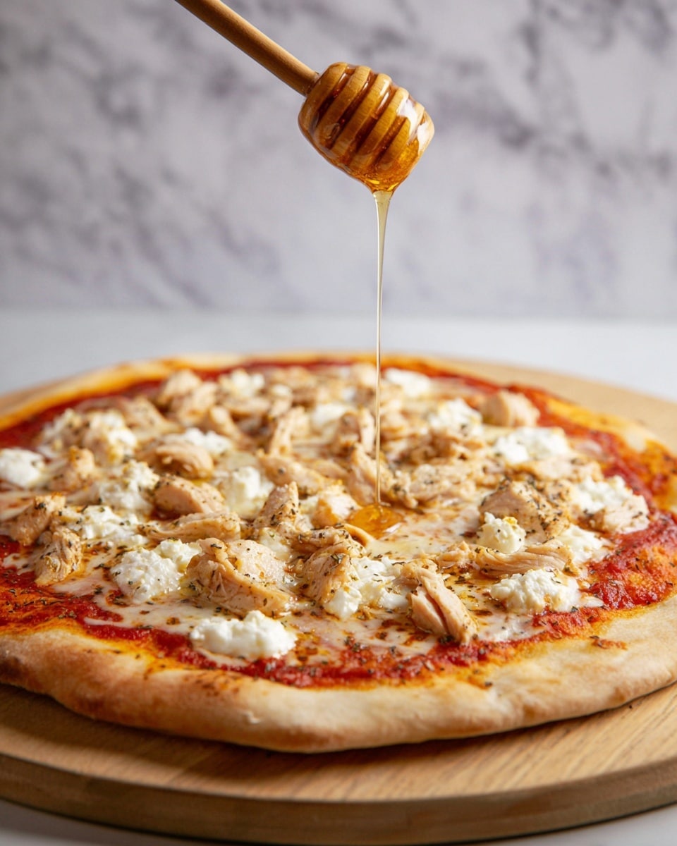 A pizza with three visible layers starts with a golden-brown crust at the bottom, followed by a bright red tomato sauce spread evenly over the dough. On top, there is a layer of melted white mozzarella cheese mixed with small dollops of creamy white ricotta cheese, scattered across the pizza. Over the cheese, there are bite-sized pieces of light brown cooked chicken seasoned with herbs, giving a speckled look. Above this, a woman's hand holds a wooden honey dipper dripping golden honey in a thin stream onto the pizza. The pizza sits on a wooden board with a background of white marbled texture. photo taken with an iphone --ar 4:5 --v 7