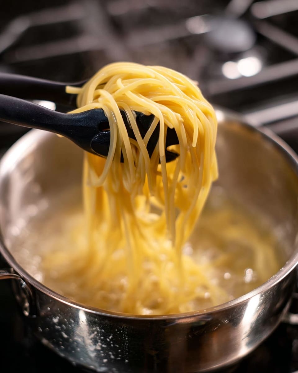 A close-up image shows light yellow spaghetti noodles being lifted from a pot of boiling water with a black pasta server that has prongs. The spaghetti strands look soft and slippery, hanging down from the pasta server into the pot. The pot is silver with a shiny, slightly worn surface, sitting on a stove burner. The background is blurred, focusing entirely on the steaming pasta being lifted. photo taken with an iphone --ar 4:5 --v 7