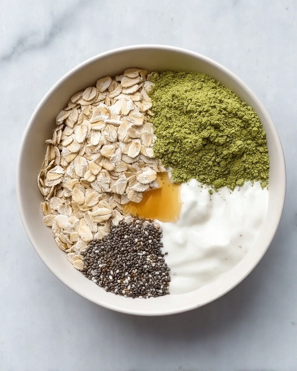 A white bowl filled with four distinct sections of ingredients placed side by side. One section shows light beige rolled oats with a rough texture, another has a bright green powder with a fine texture, the third contains smooth white yogurt with a small drizzle of honey on top, and the fourth section is filled with small black chia seeds that have a rough, grainy look. The bowl is on a white marbled surface. photo taken with an iphone --ar 4:5 --v 7