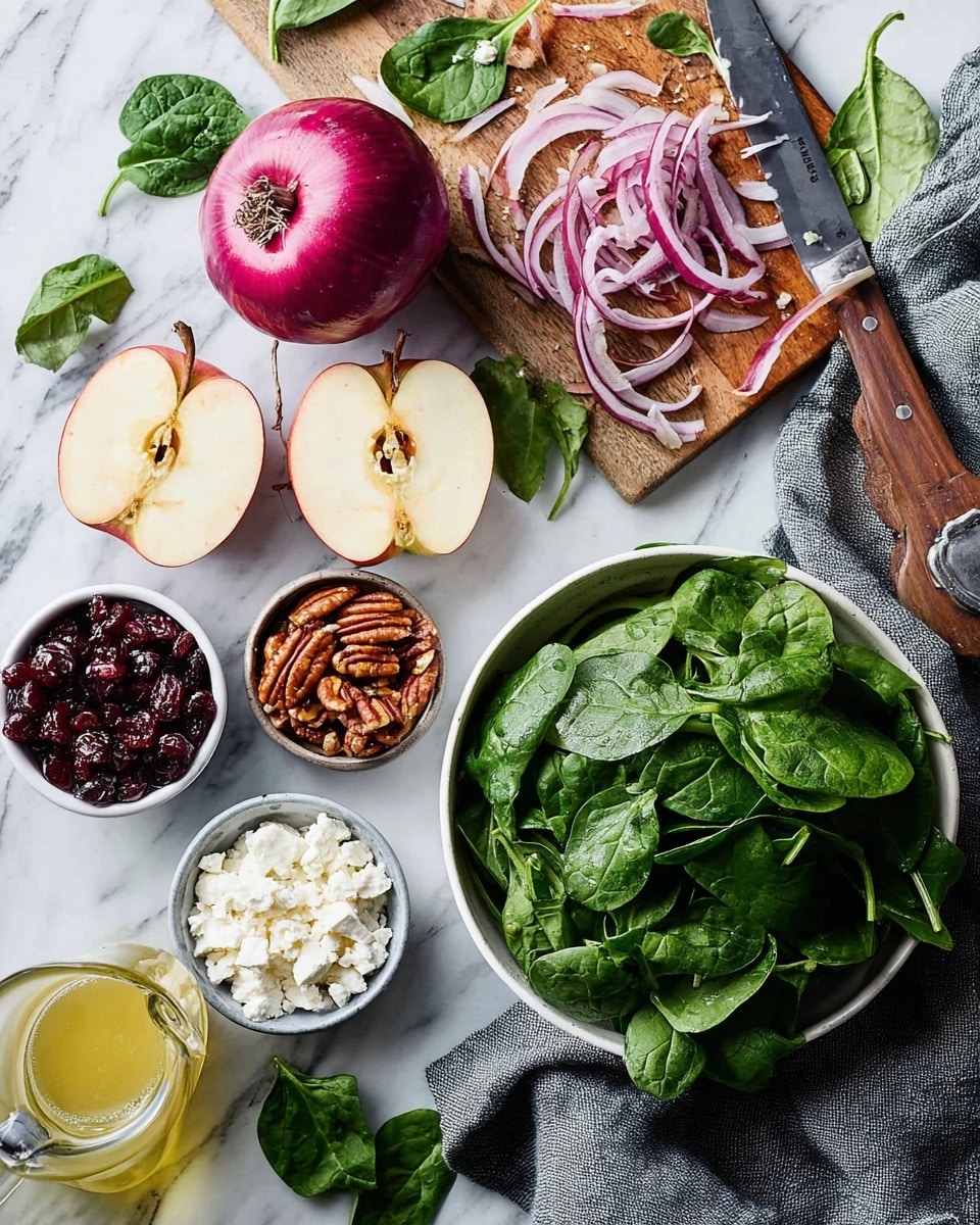 The image shows fresh ingredients arranged on a white marbled surface for a salad. In the top right, a white bowl is full of bright green spinach leaves. On the cutting board nearby, there is a purple onion, some slices are thin and curved, and a knife with a wooden handle lies next to it. Around the board, there are extra spinach leaves. To the left, two halves of a red apple with pale flesh are placed side by side. Small bowls hold white crumbled cheese, dried dark red cranberries, and brown pecan nuts. A glass bottle with light yellow dressing is also visible. A grey cloth is draped at the bottom right corner. photo taken with an iphone --ar 4:5 --v 7