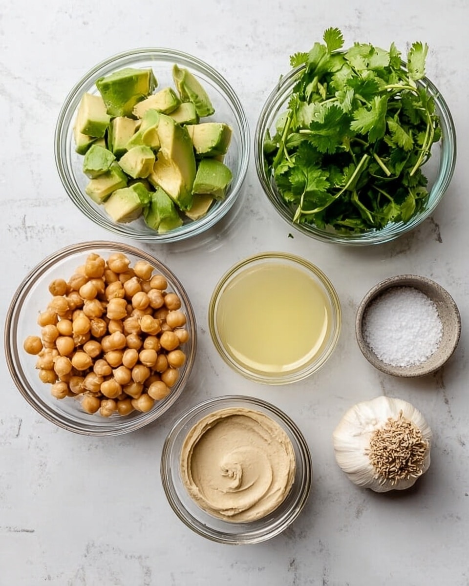 The image shows six small, clear glass bowls arranged on a white marbled surface. The top row has a bowl of sliced avocado chunks on the left and a bowl filled with fresh green cilantro leaves on the right. Below them, from left to right, there is a bowl with light brown chickpeas, a bowl containing creamy beige tahini sauce, a bowl with pale yellow lemon juice, and a small bowl with white salt. Two cloves of garlic rest on the surface near the top right corner. Photo taken with an iphone --ar 4:5 --v 7