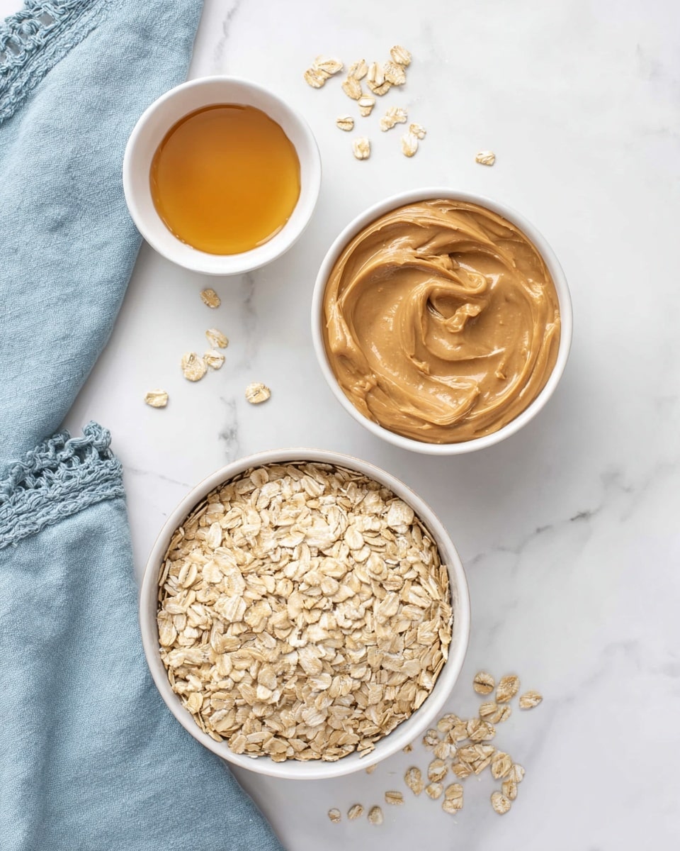 The image shows three white bowls placed on a white marbled surface. The largest bowl at the bottom contains light beige rolled oats with a rough texture, filling the bowl completely. To the upper right is a medium white bowl filled with smooth, light brown peanut butter that is spread evenly with soft swirls. The smallest white bowl to the upper left holds golden honey with a shiny and slightly thick texture. Some rolled oats are scattered around the bowls, and there is a light blue cloth with a decorative edge folded partially visible in the top left corner. Photo taken with an iphone --ar 4:5 --v 7