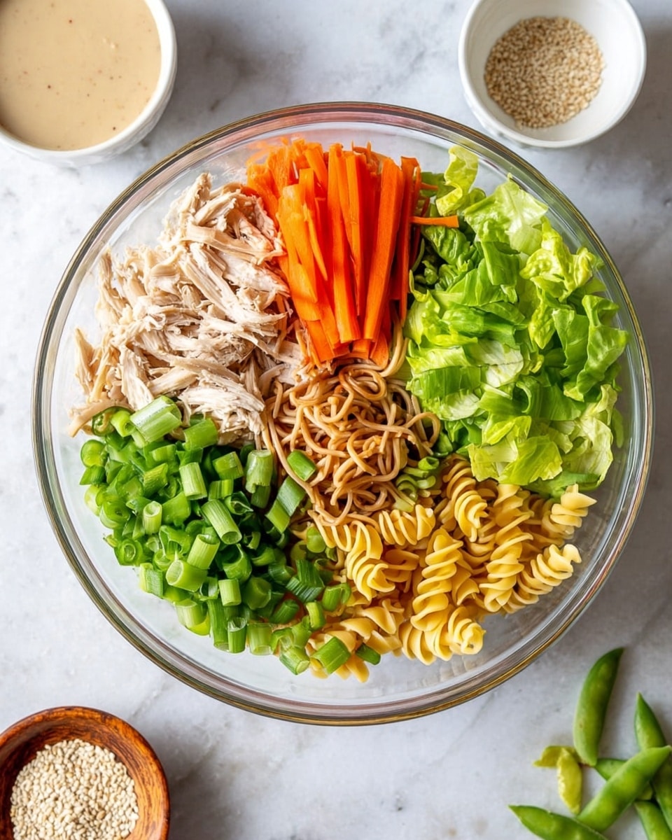 A clear glass bowl shows a salad with seven layers, each placed separately. Starting from the top left, there is shredded light beige chicken, thin round slices of light tan water chestnuts, and thin orange carrot sticks. Below these, bright green chopped scallions and whole snap peas sit next to crunchy light brown chow mein noodles. Fresh green lettuce leaves and curly yellow pasta spirals finish the bottom right side. Around the bowl on a white marbled surface, there is a small white bowl with creamy light brown dressing and a small wooden bowl with pale sesame seeds, along with a few snap peas and chow mein noodles scattered nearby. Photo taken with an iphone --ar 4:5 --v 7