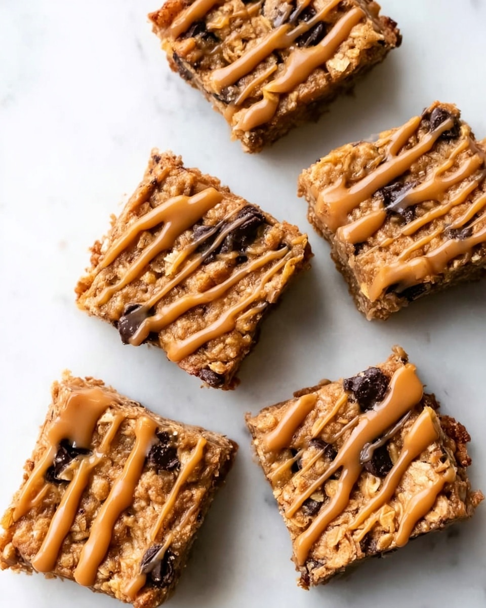 Five square pieces of chewy cookie bars placed on a white marbled surface. Each bar has a golden brown baked base textured with oats and dark chocolate chips visible throughout. The top is drizzled with a light caramel colored sauce in thin, uneven lines crossing the surface. The bars show a rough, slightly crumbly edge and a soft, moist inside. The photo taken with an iphone --ar 4:5 --v 7