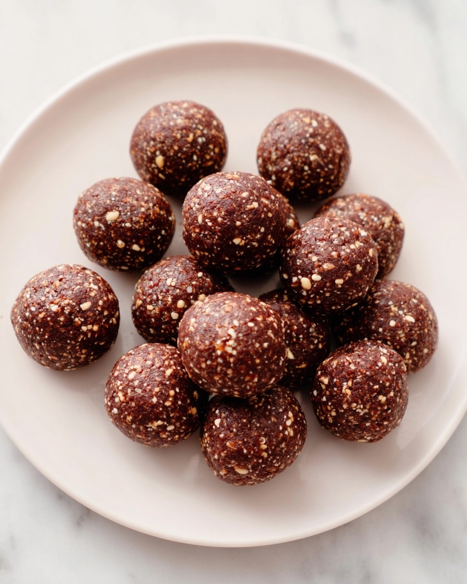 There are twelve round energy balls on a large white plate. Each ball is dark brown with small light tan bits mixed throughout, giving them a slightly rough texture. The balls are arranged closely together in a loose cluster in the center of the plate. The background is a white marbled surface. photo taken with an iphone --ar 4:5 --v 7