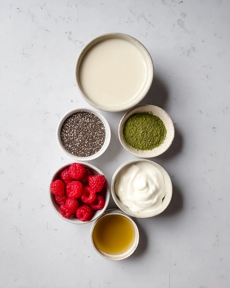 The image shows six white bowls on a white marbled surface. The largest bowl at the top contains a smooth, light cream liquid. Below it to the right is a smaller bowl filled with thick white yogurt. To the left of the yogurt is another small bowl full of tiny, dark chia seeds. Below the chia seeds is a tiny bowl with fine green matcha powder. To the right of the matcha powder is a bowl filled with bright red fresh raspberries, adding a vibrant color contrast. At the bottom center is a small round bowl with a golden honey-like liquid. The bowls are neatly arranged with distinct textures and colors, creating a clean, fresh look. Photo taken with an iphone --ar 4:5 --v 7
