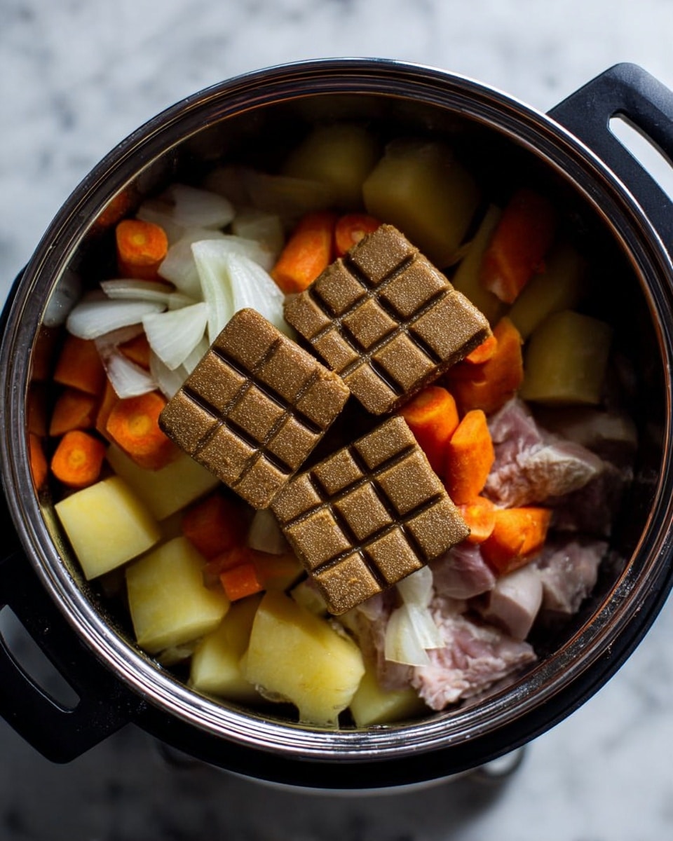Inside a black cooking pot, there are three layers of ingredients. The bottom layer shows raw small pieces of white and pinkish meat. The middle layer has chunks of orange carrot and light yellow potato, both cut roughly into pieces. The top layer consists of two large, brown, square-shaped blocks of seasoning with a grid pattern on top. Around all the ingredients, there are pieces of white onion with a slightly translucent texture. The pot is placed on a surface with white marbled texture. photo taken with an iphone --ar 4:5 --v 7