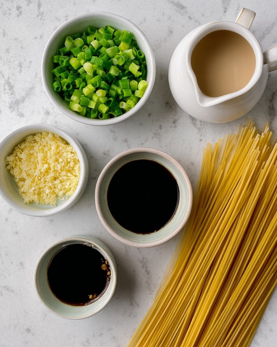 The image shows several small white bowls and a white pitcher on a white marbled surface. One bowl is full of bright green chopped scallions, and another bowl contains finely chopped light yellow garlic. A third small bowl holds a very dark liquid, while a fourth bowl is filled with a thick dark sauce. The white pitcher is filled with a light beige creamy liquid. Next to the bowls, there is a pile of uncooked thin yellow pasta strands laid out flat. The arrangement is neat and organized, with each ingredient clearly visible. photo taken with an iphone --ar 4:5 --v 7