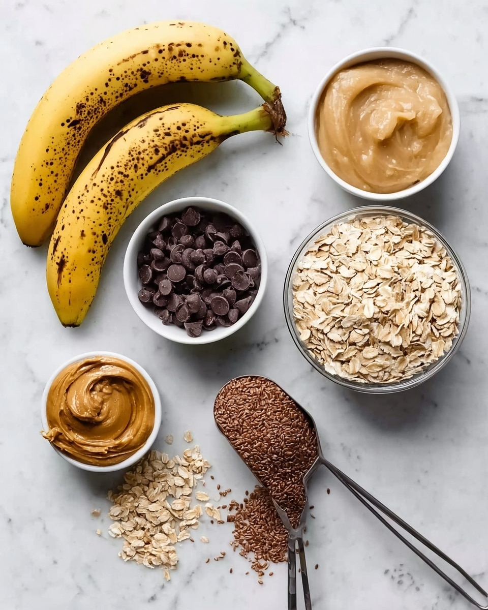 The image shows several ingredients arranged on a white marbled surface. There are two ripe bananas with brown spots at the bottom left. Above them, a white bowl filled with small dark chocolate chips sits. Next to it is a small white cup containing light beige applesauce. To the right, a large clear bowl is full of dry rolled oats. In the center, a metal spoon holds creamy peanut butter. Below the spoon, a metal scoop contains brown flaxseed meal, with some flaxseed scattered around. The overall look is clean and organized, showing a variety of textures from smooth to rough and colors ranging from brown to yellow to white. Photo taken with an iphone --ar 4:5 --v 7