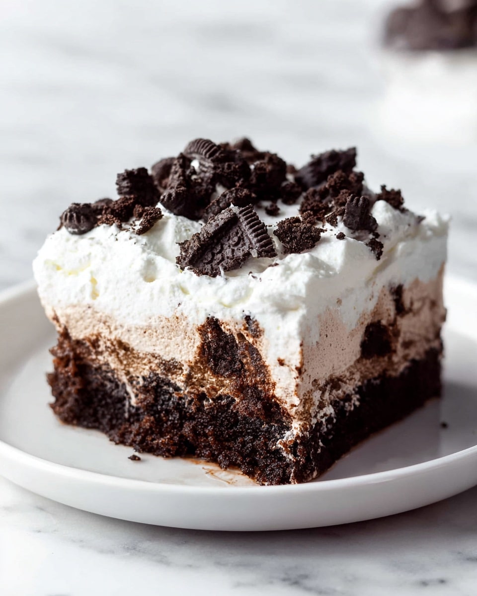 A square piece of dessert with three visible layers sits on a white plate on a white marbled surface. The bottom layer is dark brown and looks soft and moist like chocolate cake. The middle layer is lighter brown with a creamy texture that blends slightly into the cake below. The top layer is thick white whipped cream, smooth and fluffy, decorated with broken dark chocolate cookie pieces scattered on top. The edges of the cake show the mix of the creamy middle and the moist cake below. Photo taken with an iphone --ar 4:5 --v 7
