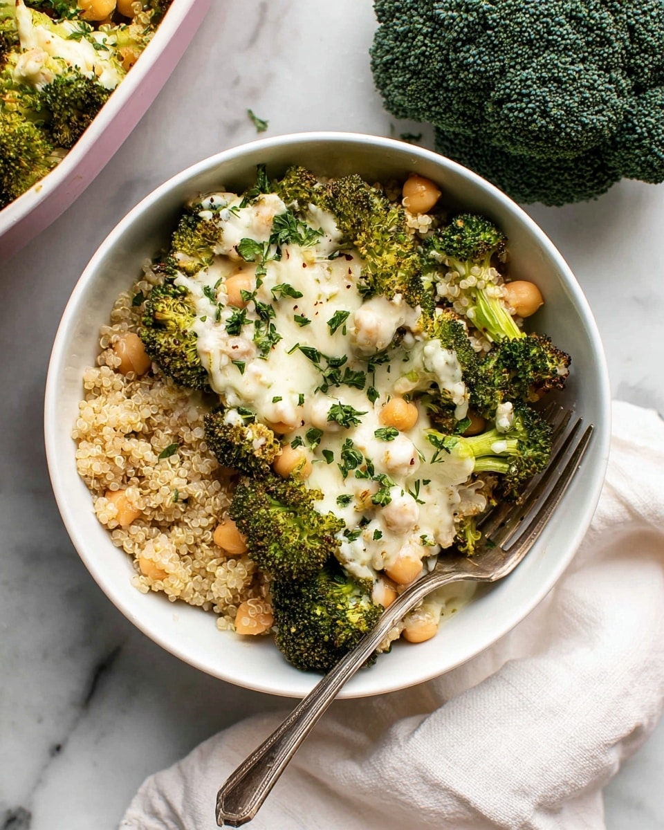 A white bowl filled with three main layers: the bottom layer is light beige quinoa grains mixed with soft beige chickpeas, the middle layer has bright green broccoli florets, and the top layer is melted white cheese drizzled over the broccoli and chickpeas, sprinkled with small pieces of fresh green herbs. A silver fork rests inside the bowl on the right side. The bowl is placed on a white marbled surface, with a large dark green broccoli head near the top right corner and a white cloth partially visible at the bottom. Photo taken with an iphone --ar 4:5 --v 7