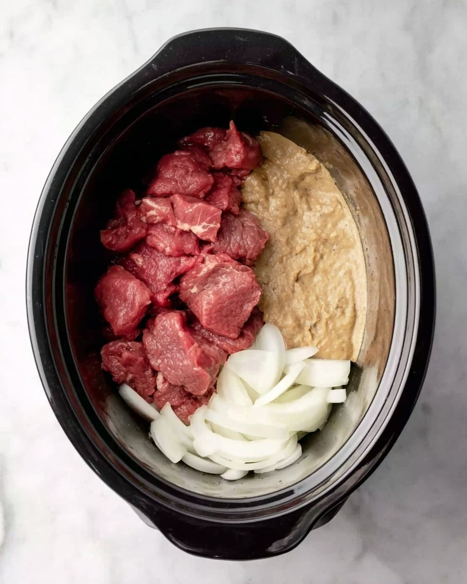 Inside a black slow cooker, there are three main layers. At the bottom, white sliced onions lay flat. On the top left side, raw red meat pieces are piled up thickly. On the top right side, a light brown creamy sauce with a slightly lumpy texture sits beside the meat. The slow cooker is on a white marbled surface. Photo taken with an iphone --ar 4:5 --v 7