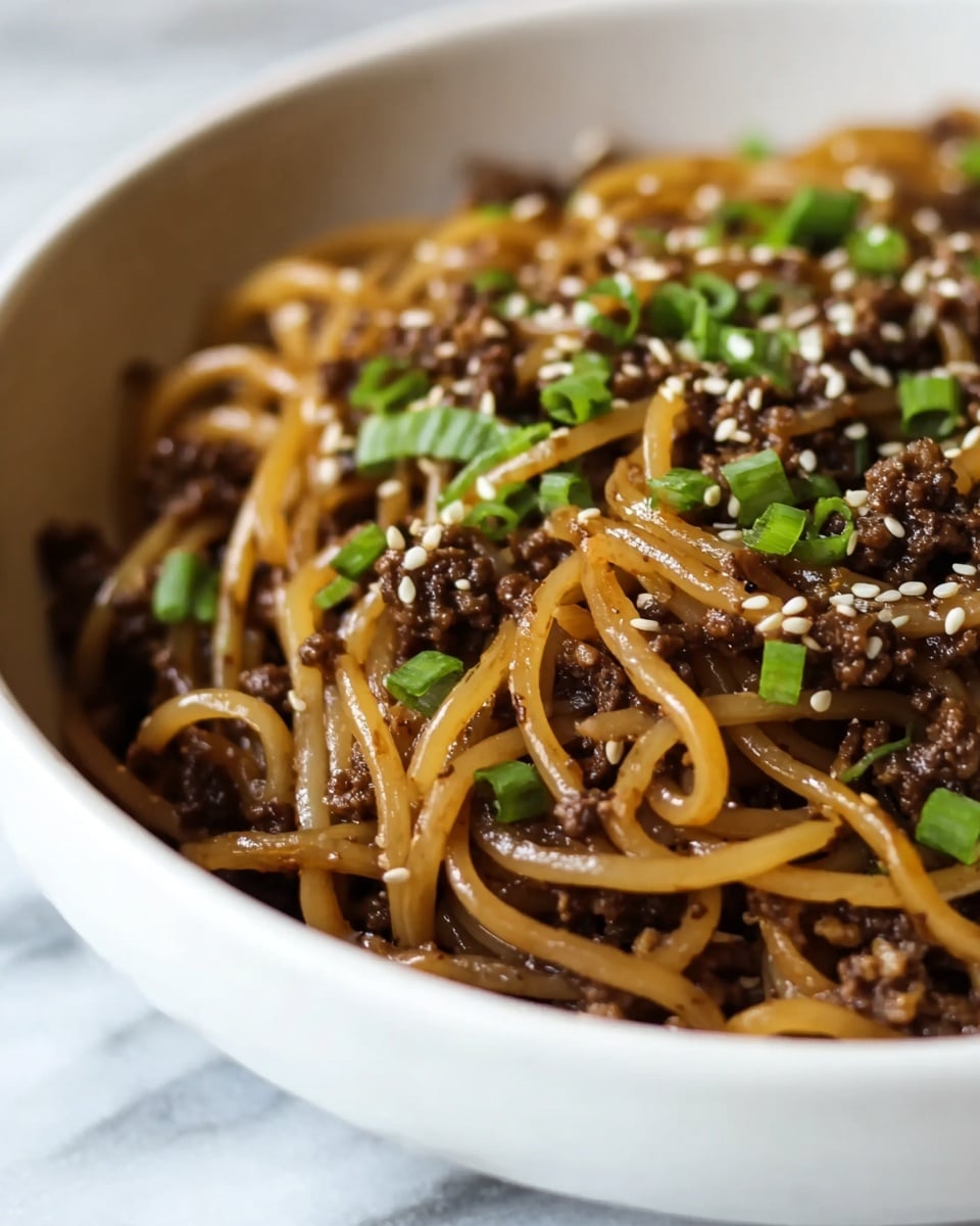 A close-up view of a white bowl filled with a mix of cooked brown noodles and finely ground dark brown meat. The noodles are soft and shiny, twisted around each other with the meat spread evenly between them. Small white sesame seeds are scattered on top, along with bright green chopped scallions adding a fresh color contrast. The bowl sits on a white marbled surface, and the focus highlights the texture of the noodles and toppings photo taken with an iphone --ar 4:5 --v 7