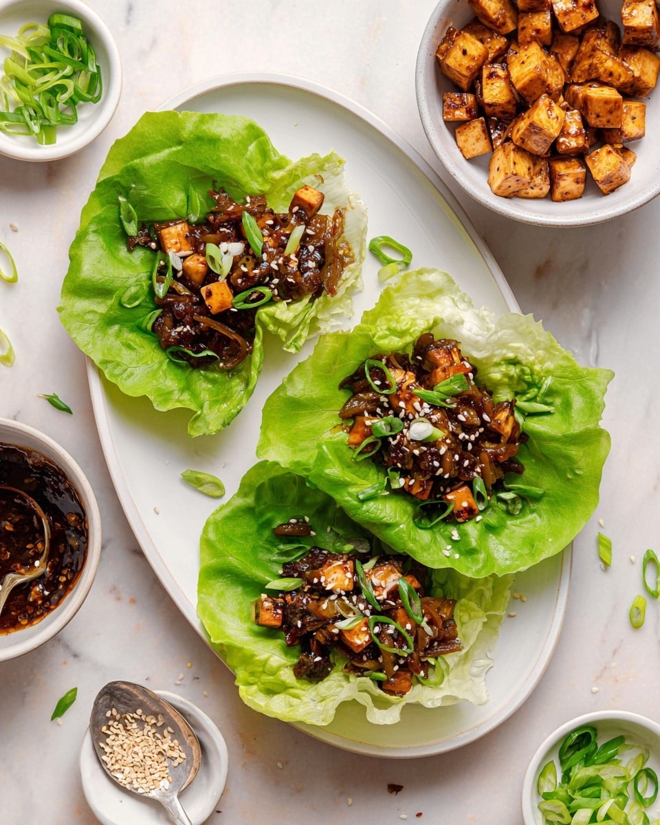 The image shows three fresh green lettuce cups placed on a white oval plate with a white marbled surface underneath. Each lettuce cup holds a filling of small brown tofu cubes mixed with darker sauce-coated bits, topped with thinly sliced green onions and white sesame seeds. Around the plate, there are separate white bowls: one contains more small tofu cubes, one has green onion slices, and one has a dark sauce with small pieces and a silver spoon. A few lettuce leaves and scattered sesame seeds and green onion pieces are on the white marbled surface. photo taken with an iphone --ar 4:5 --v 7