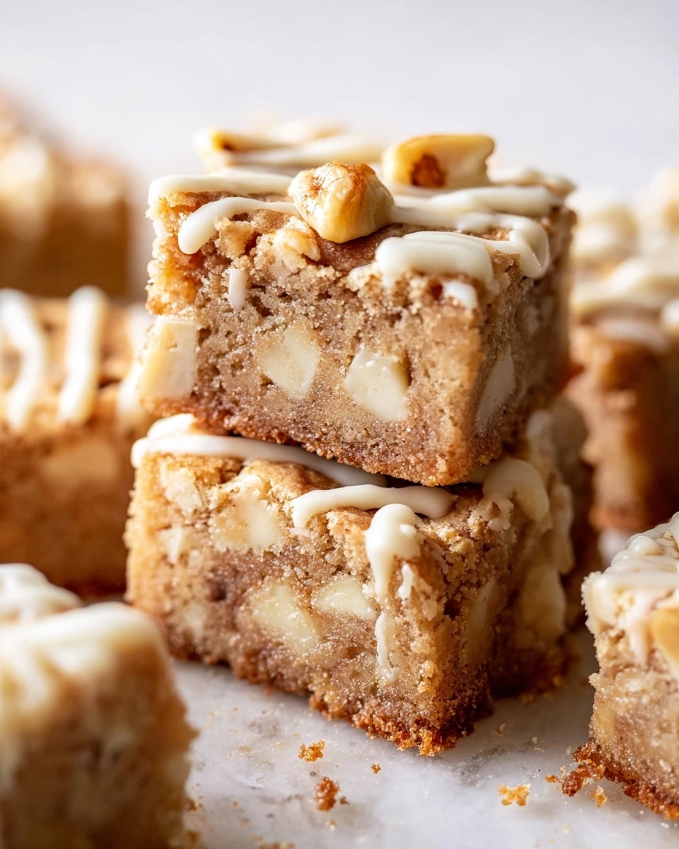 The image shows a close-up of several square blondies stacked on a white marbled surface. Each blondie has two main layers: a dense, light brown base filled with white chocolate chunks, and a top layer covered with a drizzle of creamy white icing. Small pieces of nuts are scattered on top, adding texture and contrast. The blondies have a slightly crumbly texture around the edges, and the overall color palette includes warm browns, creamy whites, and hints of golden nuts. Photo taken with an iphone --ar 4:5 --v 7
