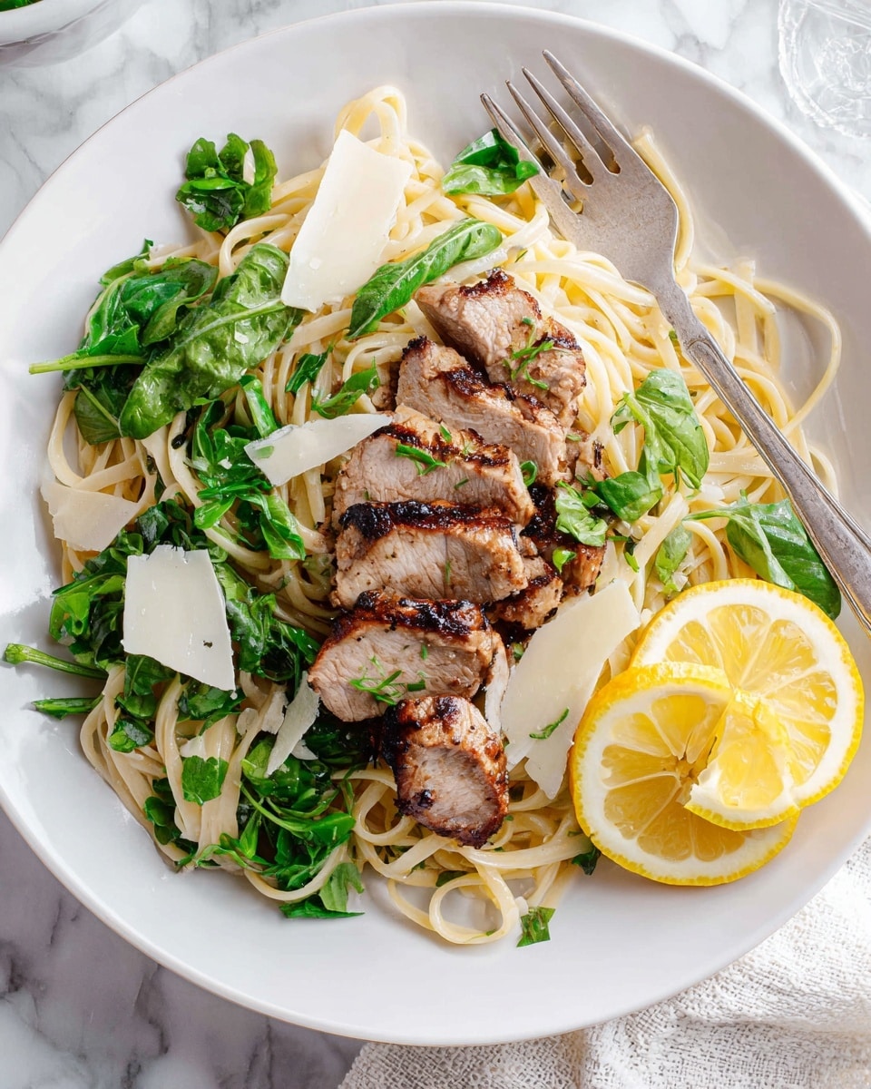 A white plate holds a dish with three main layers: the bottom layer is light-colored noodles arranged loosely, the middle layer has fresh bright green leafy herbs scattered on top of the noodles, and the top layer features several slices of grilled meat with seeded brown edges placed centrally. On the right edge of the plate, two lemon wedges with a bright yellow color rest beside a silver fork that is partly on the noodles. Thin, off-white cheese slices are sprinkled over the dish. The plate sits on a white marbled surface with a white textured napkin partially visible on the right side. photo taken with an iphone --ar 4:5 --v 7