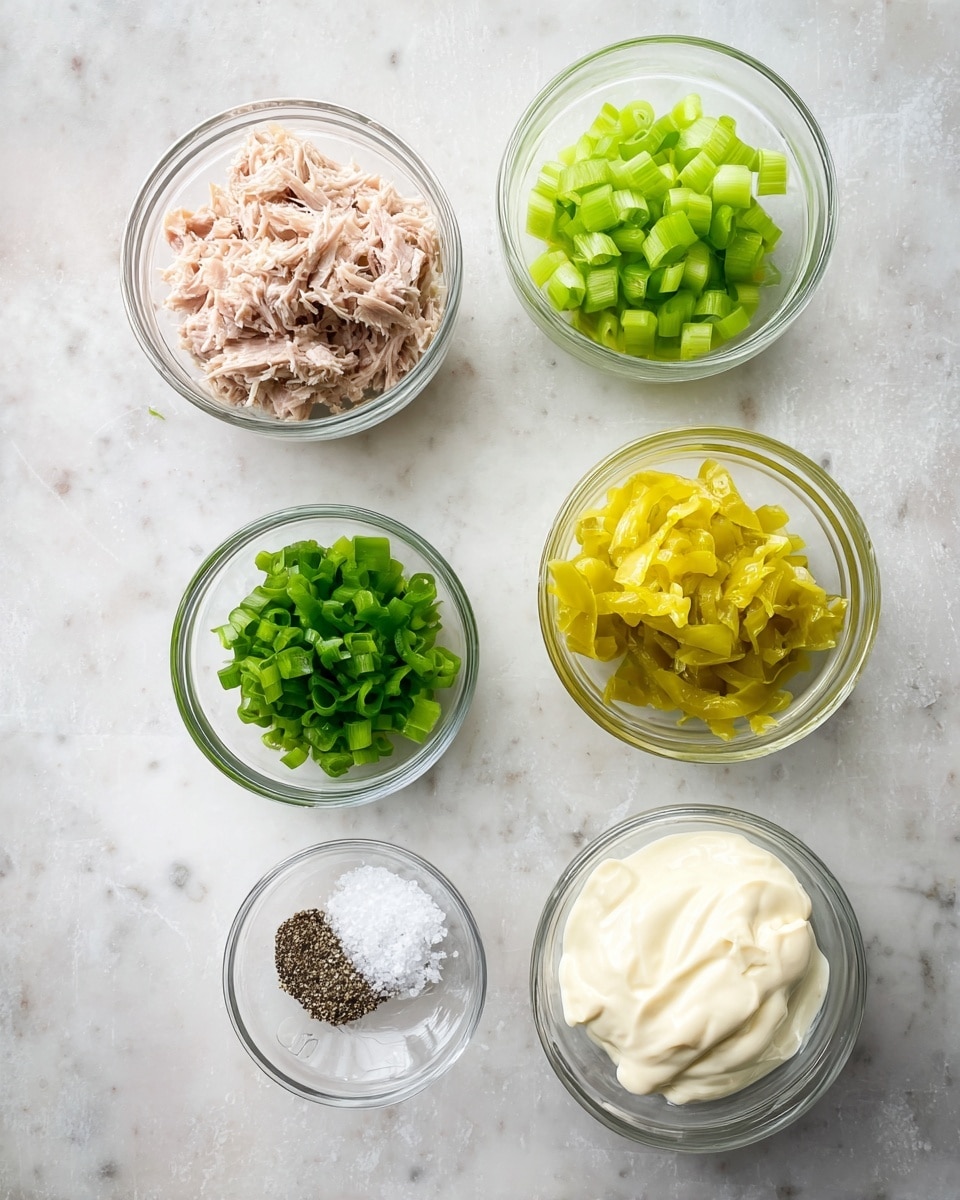 Five small clear glass bowls are arranged on a white marbled surface. The top left bowl holds shredded light pink tuna. Below it, another bowl contains bright green chopped celery. To the right of the tuna, there's a bowl filled with yellow pickled peppers. Below the celery is a bowl with chopped green onions in two shades of green. To the right of the onions, a bowl is filled with white creamy mayonnaise. On the surface between the bowls are small piles of white salt and black pepper. Photo taken with an iphone --ar 4:5 --v 7