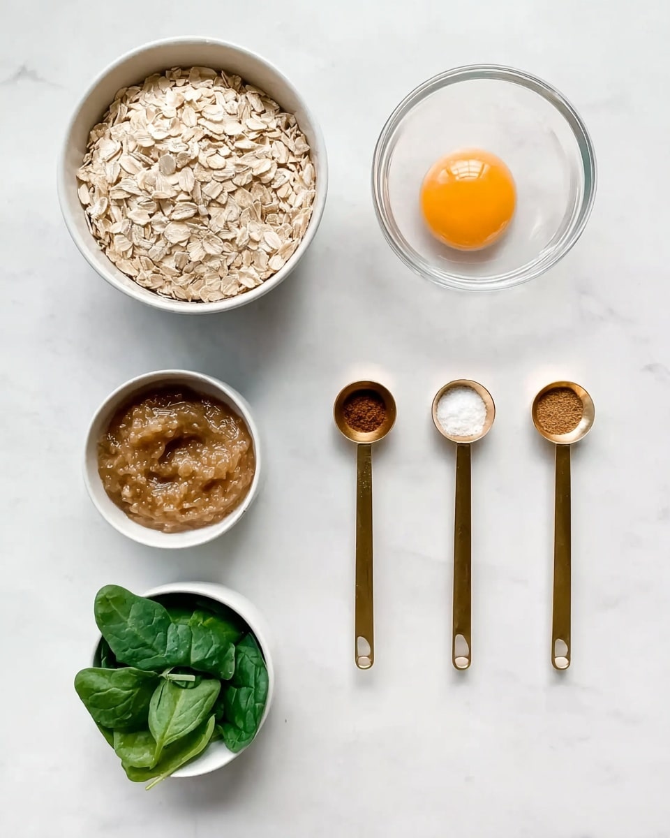 The image shows six small white bowls and three gold measuring spoons arranged on a white marbled surface. The top left bowl is filled with light beige rolled oats. To the right, a clear glass bowl holds a single raw egg yolk on a white background. Below the oats is a small bowl with light brown applesauce, and next to it is a bowl with fresh green spinach leaves. The three gold measuring spoons are lined up horizontally between the oats and the egg yolk, each filled with white salt, dark honey, and brown cinnamon powder from left to right. The whole scene is simple, clean, and bright. photo taken with an iphone --ar 4:5 --v 7