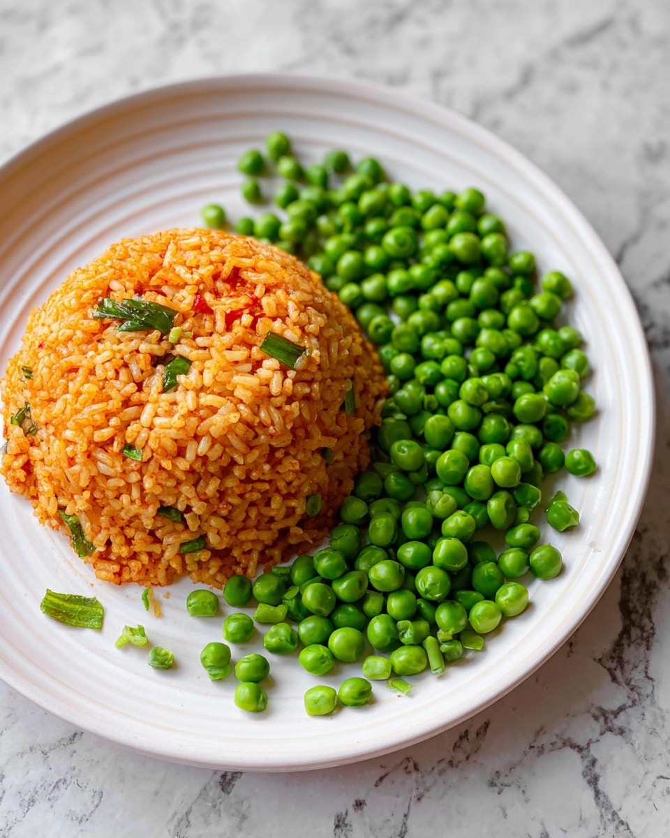 The image shows a mound of orange-colored rice shaped like a dome on the left side of a white plate. The rice is mixed with small green bits that look like herbs or scallions. On the right side of the plate, there is a pile of bright green peas, slightly scattered around the edge of the rice. The plate is placed on a white marbled surface. The food looks warm and fresh. photo taken with an iphone --ar 4:5 --v 7