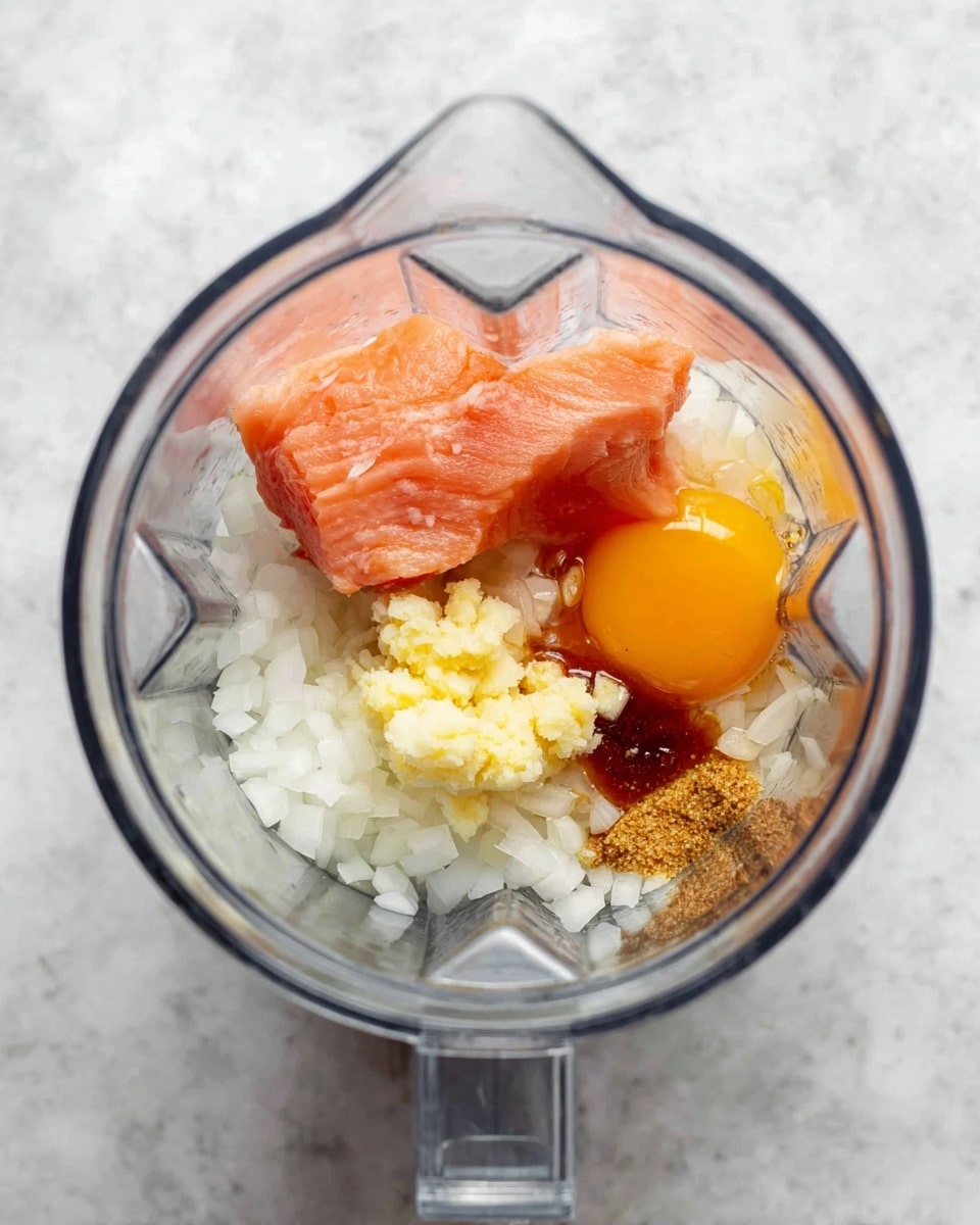 Inside a clear blender jar on a white marbled surface, there are five visible layers and ingredients: at the bottom, white chopped onion pieces fill much of the space; on the left side, a smooth piece of raw pink salmon sits; next to the salmon, a dollop of pale yellow minced garlic rests; to the right, a bright orange raw egg yolk lies next to the garlic; scattered lightly on top of the onions are small bits of brown sugar and a touch of dark soy sauce. photo taken with an iphone --ar 4:5 --v 7