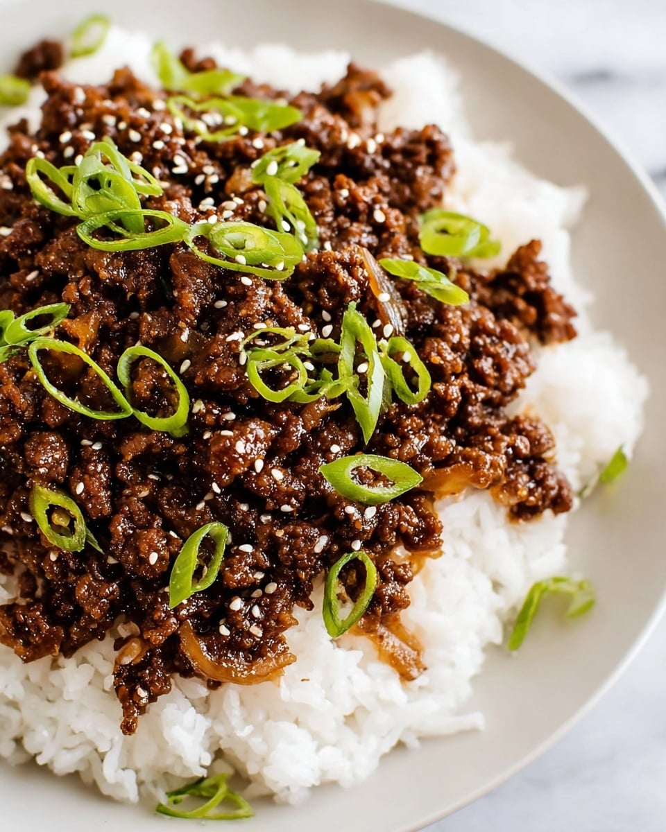A close-up view of a white plate with a base layer of white steamed rice, topped with a thick layer of dark brown cooked ground meat mixed with browned onions. The meat is garnished with thinly sliced green onions scattered on top, along with a sprinkling of small white sesame seeds. The plate sits on a white marbled surface. photo taken with an iphone --ar 4:5 --v 7