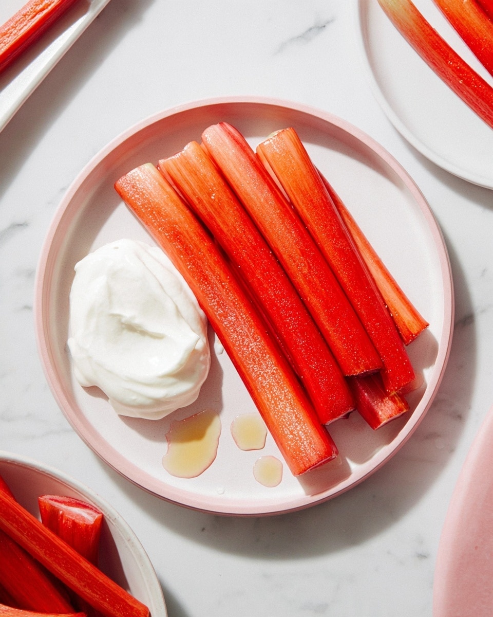 A white plate sits on a white marbled surface, holding six long, shiny red-orange stalks of rhubarb arranged side by side. On the left side of the plate, a dollop of thick, smooth white cream rests partly on top of one stalk. The rhubarb stalks have a slightly glossy texture, indicating they may be cooked or glazed. Around the plate, there are a few small drops of liquid. In the top right corner, fresh rhubarb stalks appear to rest on the white marbled surface, and at the bottom left, a white dish contains more rhubarb pieces. The photo taken with an iphone --ar 4:5 --v 7