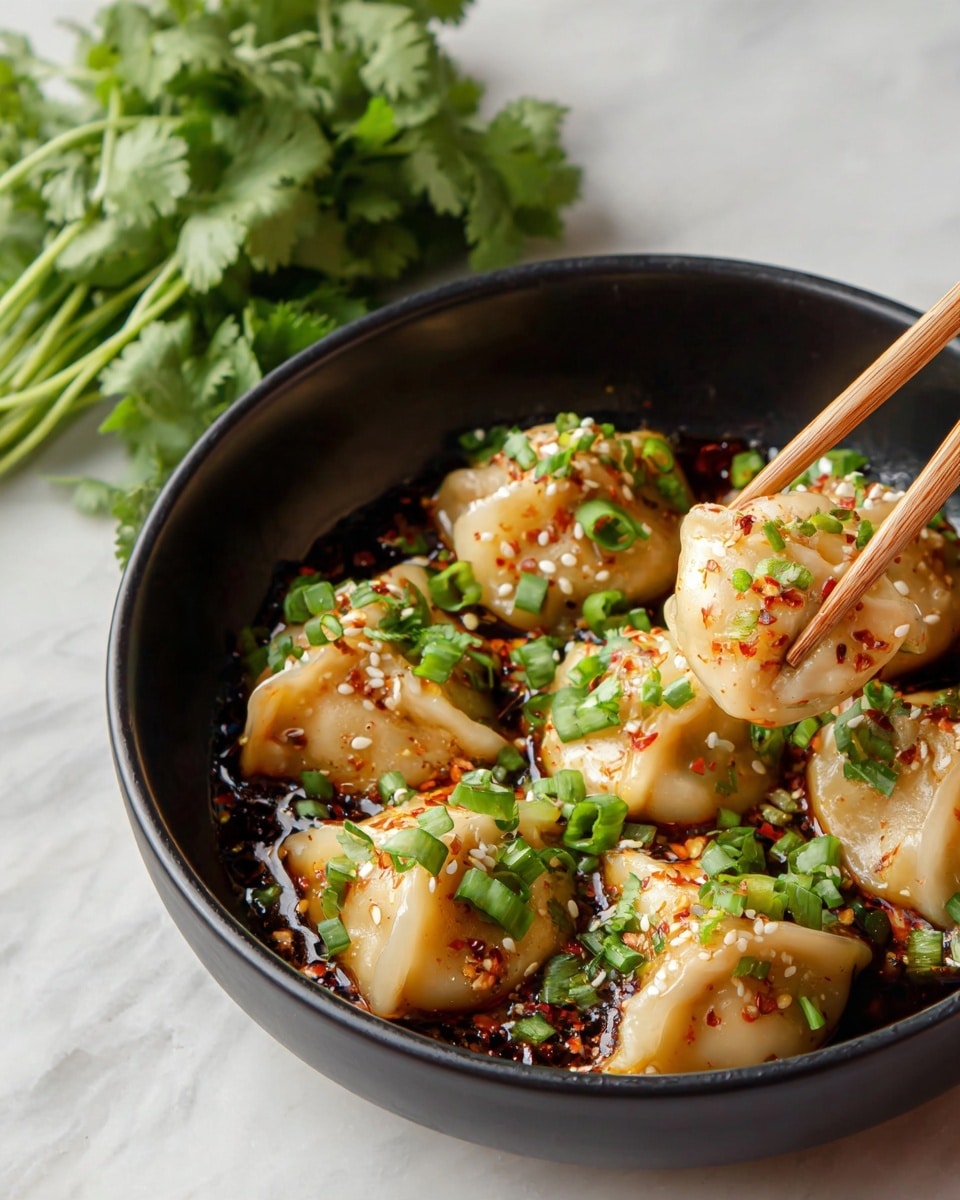 A black bowl holds six steamed dumplings, each with a smooth, pale beige wrapper folded over a filling, sitting in a dark brown sauce. The dumplings are topped with bright green chopped scallions, toasted white sesame seeds, and small bits of red chili flakes giving a spicy look. Two wooden chopsticks from the right side are holding one dumpling. In the background, there is a bunch of fresh green cilantro on a white marbled surface. Photo taken with an iphone --ar 4:5 --v 7
