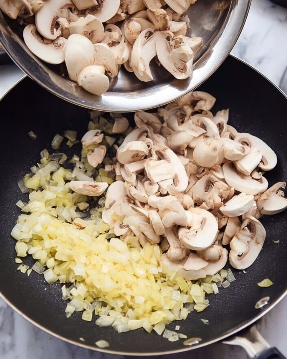 The image shows a black frying pan with a layer of small, chopped light yellow onions evenly spread at the bottom. On top of the onions, there is a large pile of whole and sliced pale beige mushrooms, with some mushrooms visibly falling from a shiny silver bowl held above the pan. The background and surface are a white marbled texture. Photo taken with an iphone --ar 4:5 --v 7
